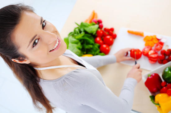 Young woman in her kitchen cutting ingredients.