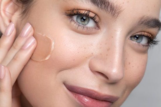 Young woman with perfect skin applying foundation